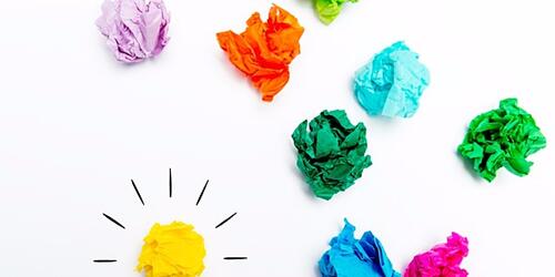 Yellow lightbulb made from scrunched up paper, surrounded by other coloured scrunched up paper